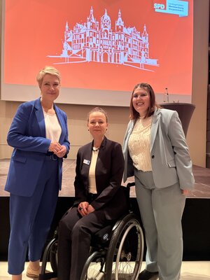 von links Manuela Schwesig im blauenm Anzug mit weißer Bluse daneben Jana Schulz mit einem schwarzen Anzug und weißer Bluse und ganz rechts Laura Golz mit mintfarbenden Anzug und weißen Oberteil mit Rüschen